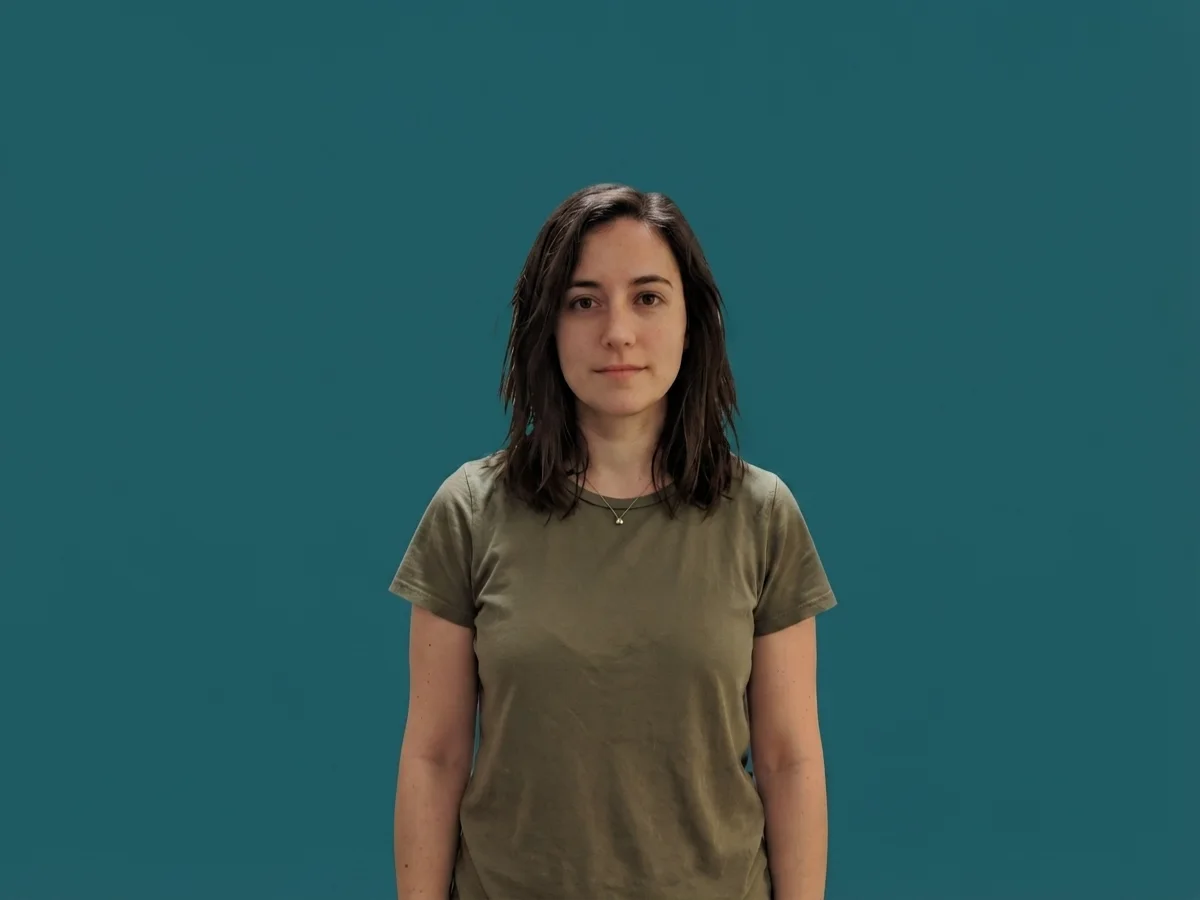 The same woman against a flat solid deep-teal background