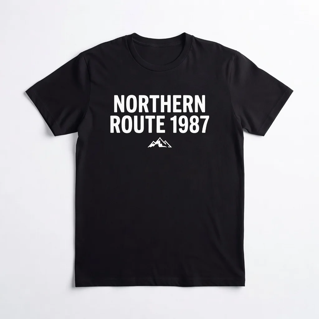 Product photo of a black t-shirt with a white chest print reading NORTHERN ROUTE 1987 above a mountain logo